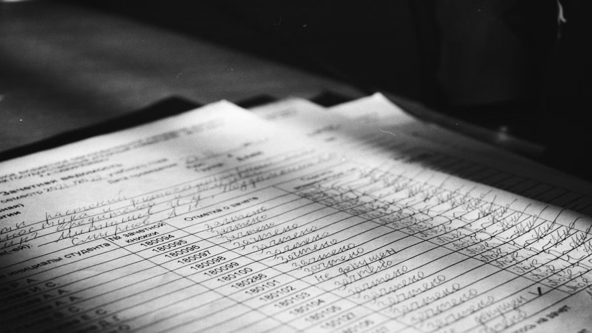 Close-up grayscale photo of a handwritten document with visible text and shadows.